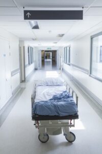 An empty hospital bed in an empty long white corridor 